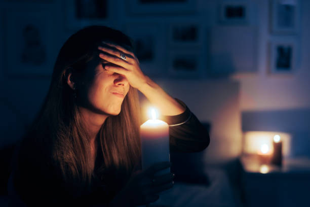 Unhappy person sitting in the dark at candlelight alone