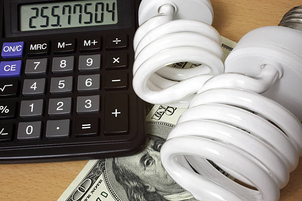 "Lightbulbs, calculator and Hundred dollar bill as a symbol of savings from the use of Compact Fluorescent Lightbulb."
