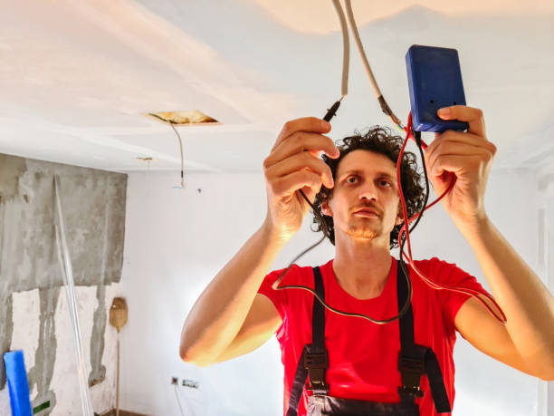 Electrician connecting wires in ceiling while renovating house.