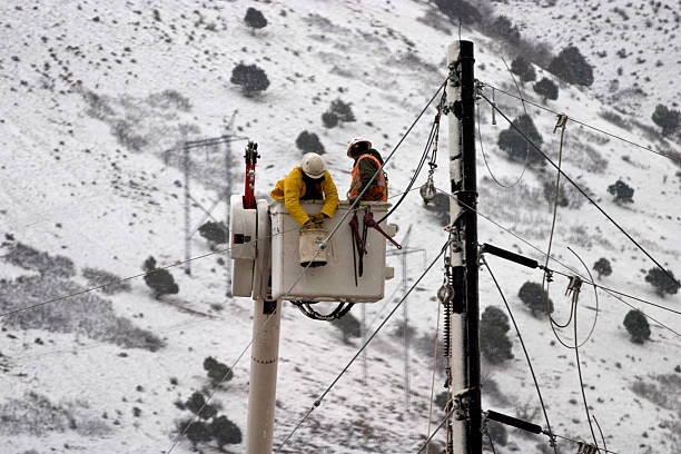 Two workers in bucket truck doing construction work on power lines.