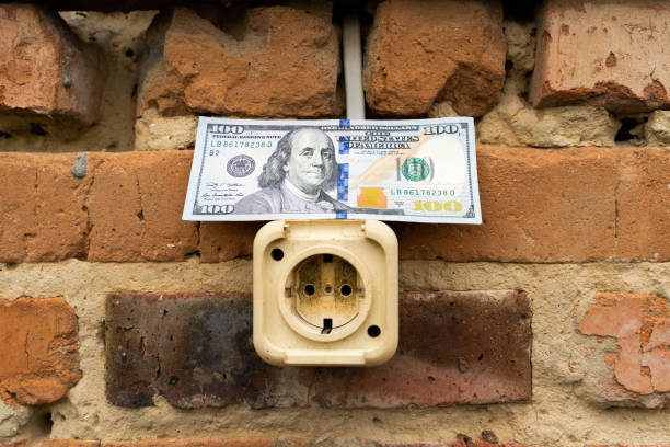 One hundred us dollars lie on a street electrical outlet on an old brick wall close-up. Money and electrical wiring repair. Cash investment in building renovation