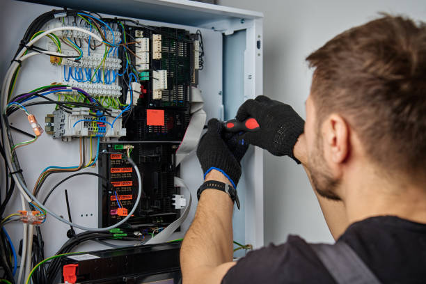 Technician working on internal wiring of heat pump, inspecting electrical connections. Specialist servicing heating and cooling system. Electrician with screwdriver tightening screws on control panel