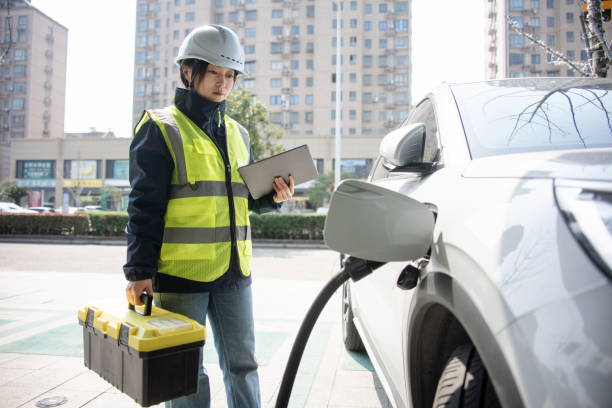 Asian female engineers working with digital tablet at the electric vehicle charging station.
