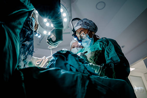 Two surgeons and an instrument technician in an operating room perform reconstructive surgery.