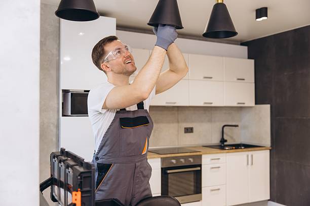 Electrician working on pendant lamp installation in a modern kitchen, ensuring proper lighting and functionality