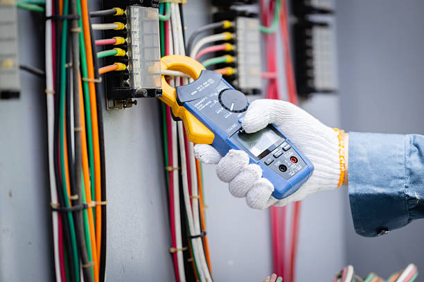 An engineer is working on high voltage power substation performing inspection and check of electrical infrastructure using specialized tools for safety and accuracy