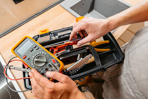 Mid-adult electrician searching for a tool in a tool box before fixing something in an apartment. Close-up.