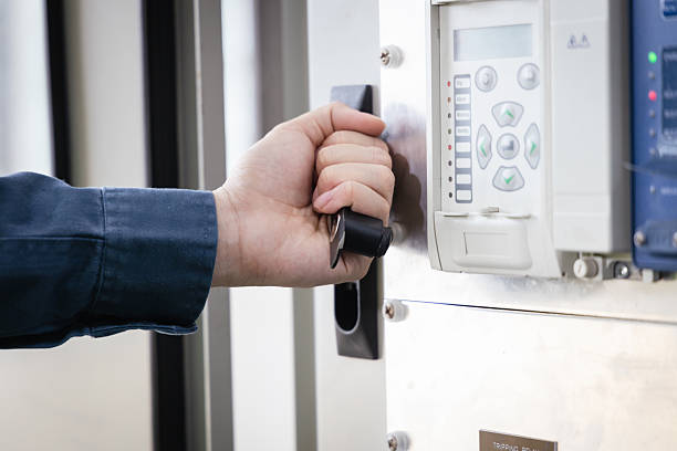 Close-up of engineer hand operating switch on electrical control panel with monitoring display, representing industrial safety, power system management, and modern energy infrastructure