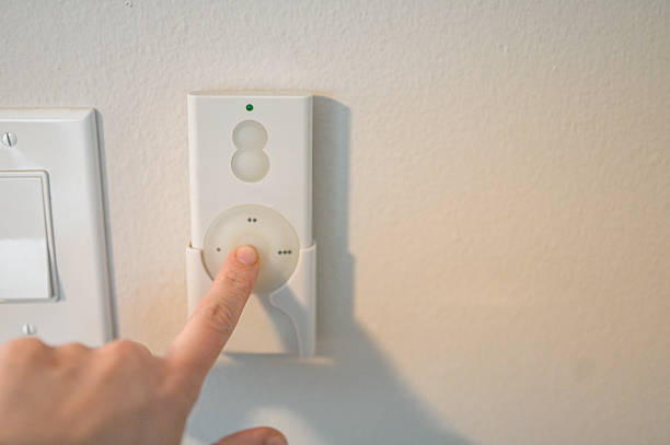 Hand pressing button on white wall-mounted remote control for smart devices