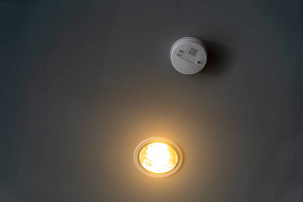 A ceiling light illuminates the room while a smoke detector hangs above, highlighting the importance of safety and modern home design in living spaces.