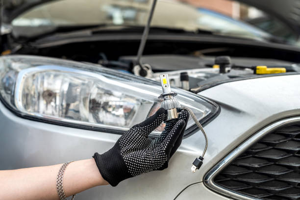 male hand holding modern LED h7 bukb near headlamp of a car