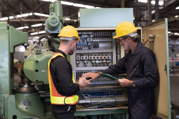 Group of male electrician worker checking, repair, maintenance electric system of CNC machine in factory. Team of male electrician engineer inspecting quality electric during manufacturing process