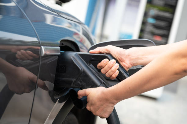 Action of person hand is plugging the CCS2 DC charger socket head with the EV car for recharging the energy. Transporation and technology concept scene, selective focus at hand part.