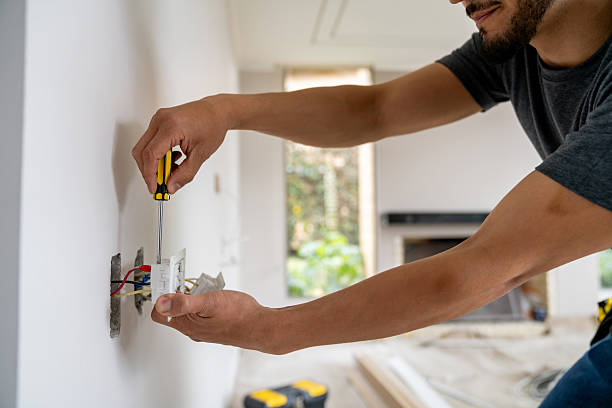 Close-up on an electrician installing a power socket while working at a construction site