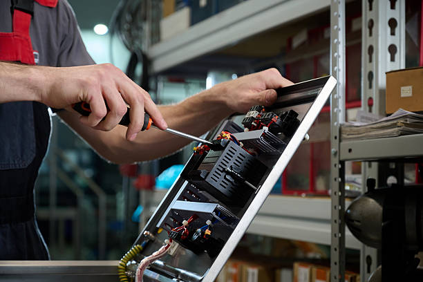 An electrician repairs and diagnoses electrical equipment. Assembling a control cabinet for a conveyor at a factory.