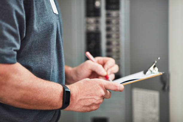 Male electrical engineer wearing a fitness tracker checking fuse box
